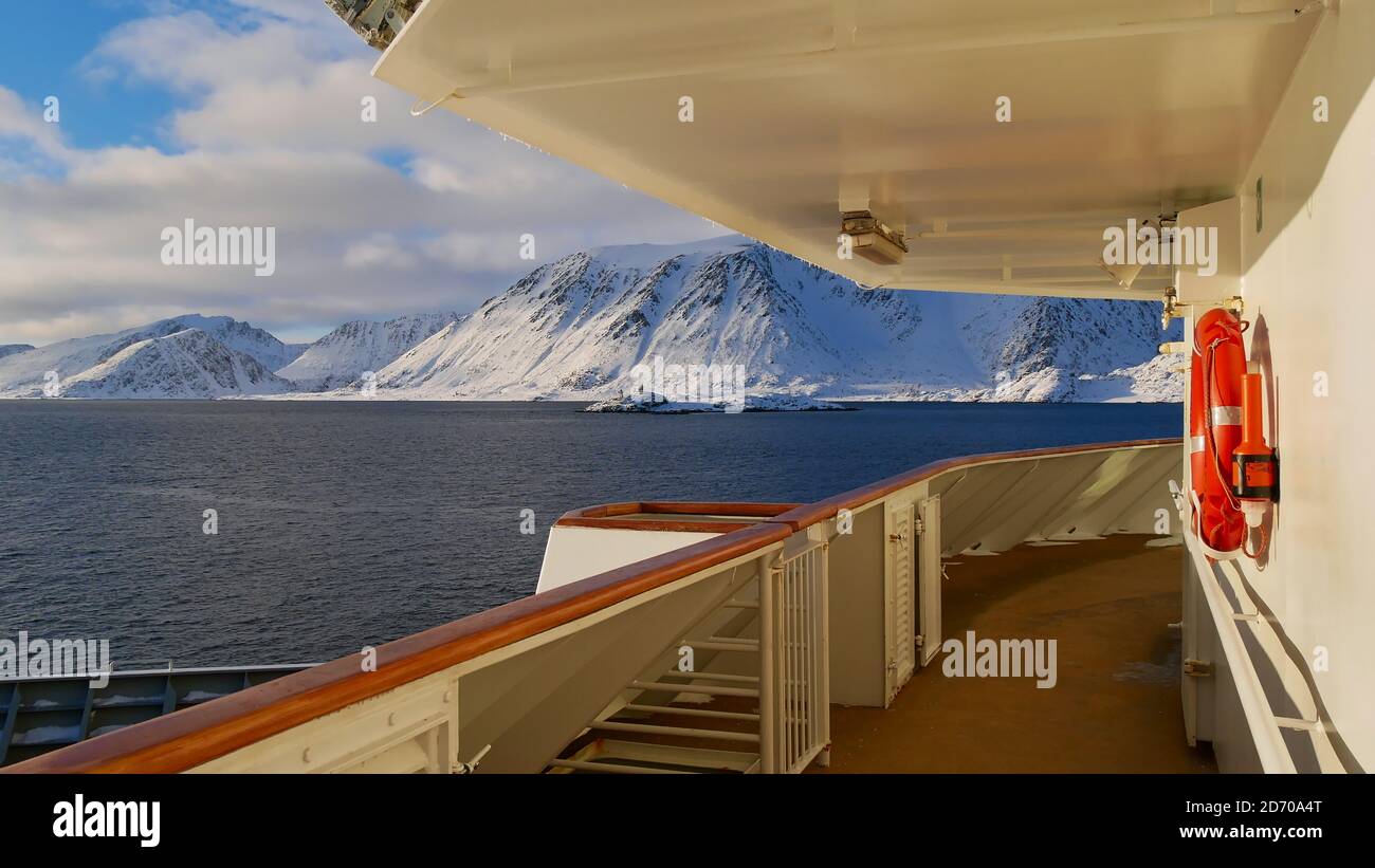 Sørøysundet, Norway - 03/02/2019: Coast of Sørøya island with snow-covered mountains in winter seen from the nose of Hurtigruten cruise ship. Stock Photo