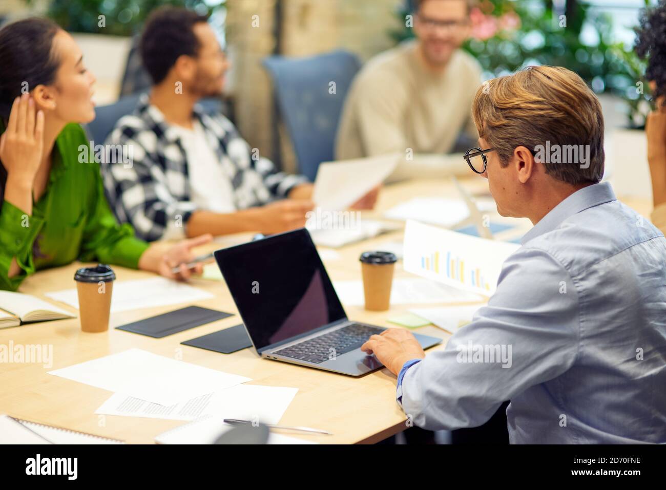 Teamwork. Group of young multiracial people sitting at the table in board room in the modern office, using modern technologies and working on project together. Business concept Stock Photo