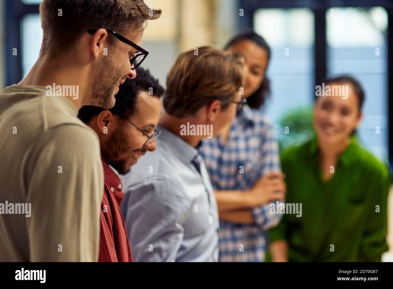 Group of happy diverse multi ethnic business people standing together in modern office and discussing project results for sharing ideas. Business, teamwork, cooperation concept Stock Photo