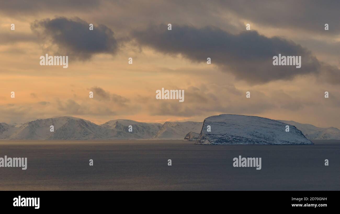 Panorama view of arctic ocean near Hammerfest, Norway, Scandinavia with the snow-covered mountains of Sørøya island in the evening light in winter. Stock Photo