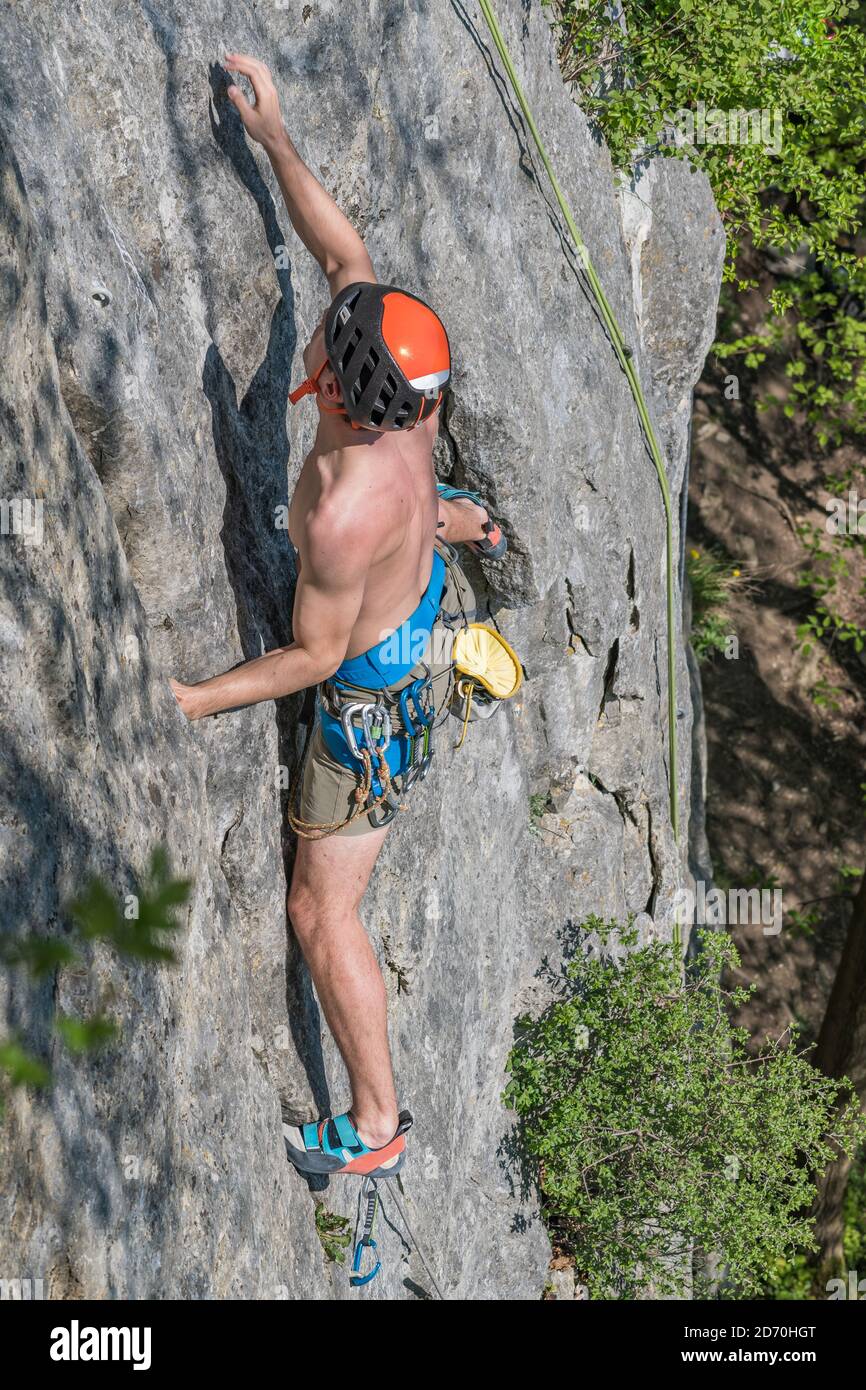 Athletic male climber moves his right hand towards the next hold. Stock Photo