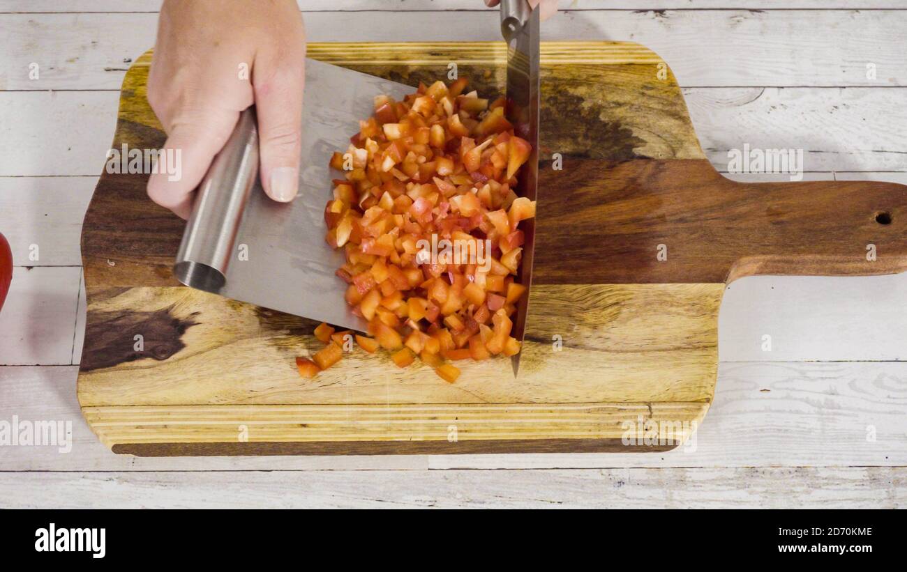 Mincing organic red bell peppers on a wood cutting board Stock Photo ...
