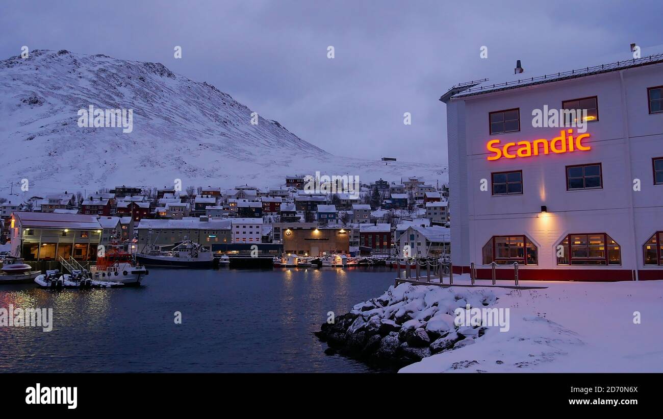 Honningsvåg, Norway - 02/27/2019: Hotel Scandic Bryggen with illuminated logo located at harbor of Honningsvåg near Nordkapp with village and snow. Stock Photo