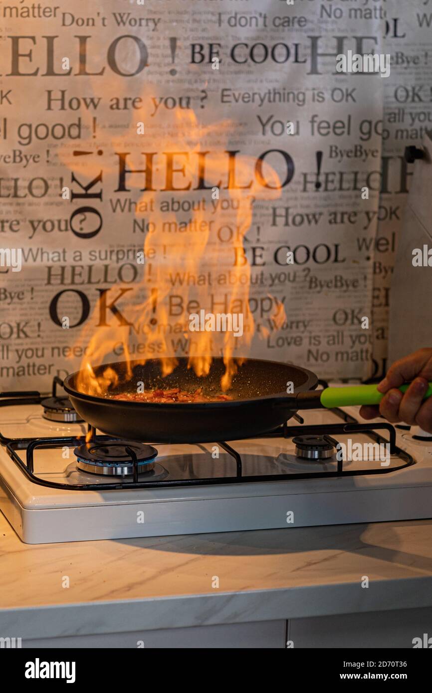 Chef cooking with flame in a frying pan on a kitchen stove Stock Photo