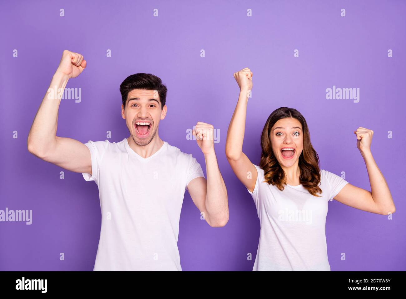 Portrait of delighted cheerful married couple man woman raise fists