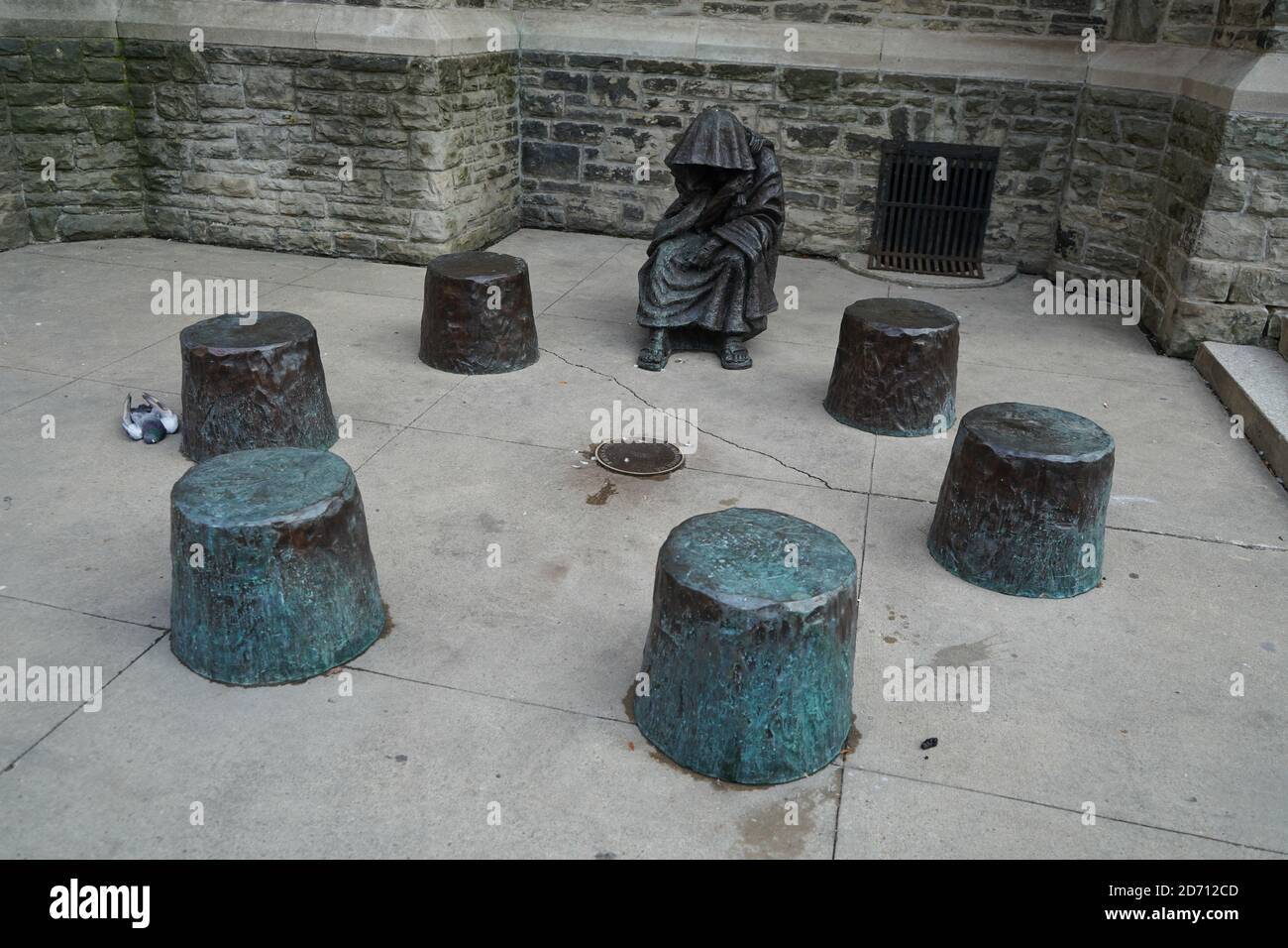 Picture of Sculpture of a man wearing a hooded cloak, sitting on a stone floor ...