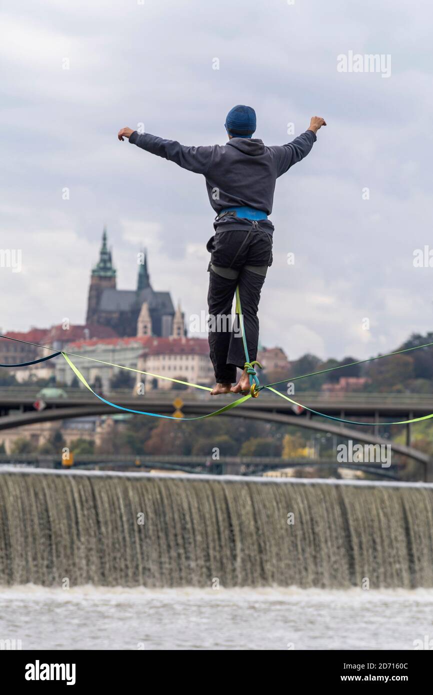 a tightrope walker on slack line above the Vltava river with background of panorama of Prague Castle, Czech republic Stock Photo