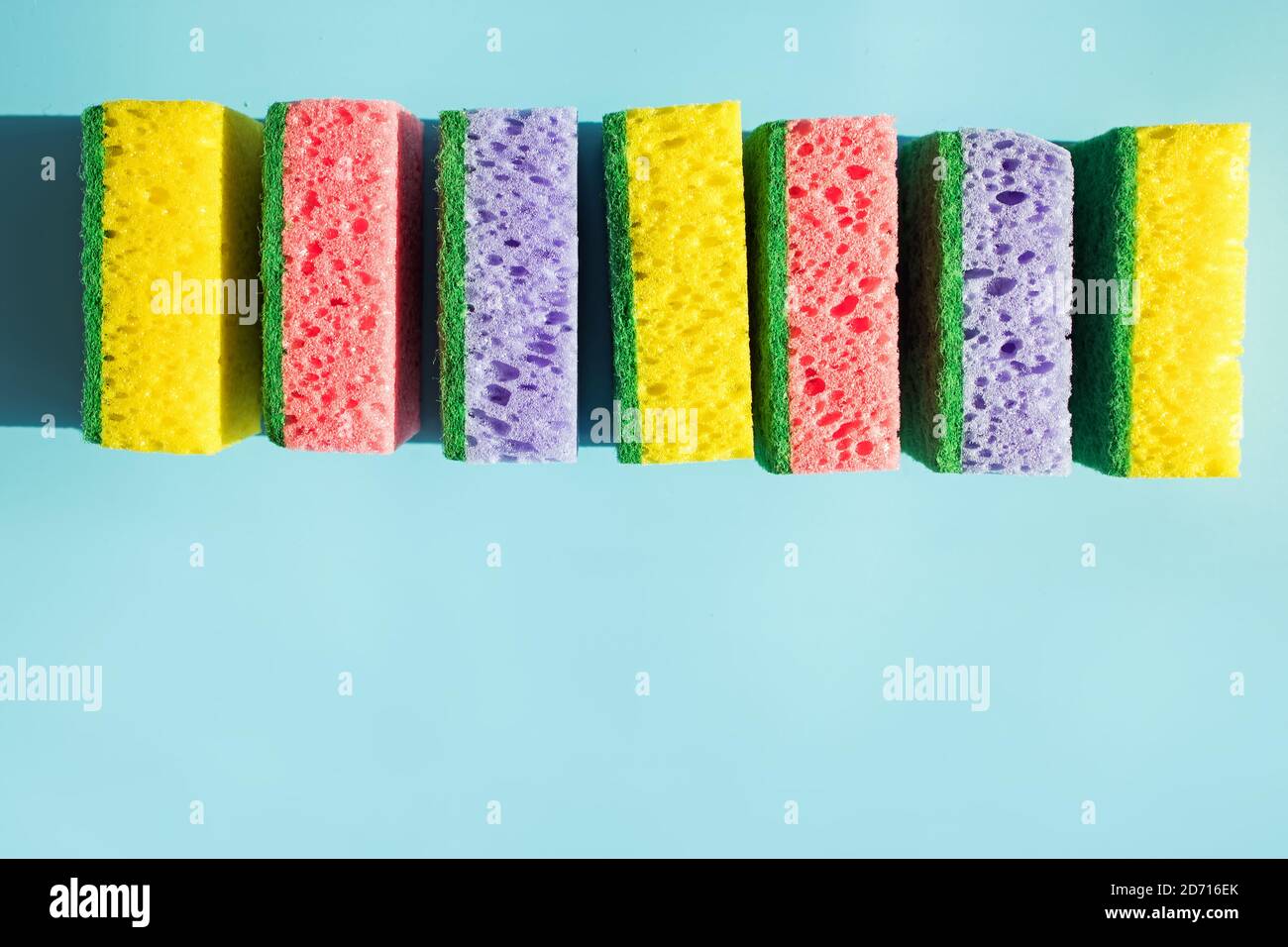 Colorful sponges for washing dishes isolated on blue background. Stock Photo