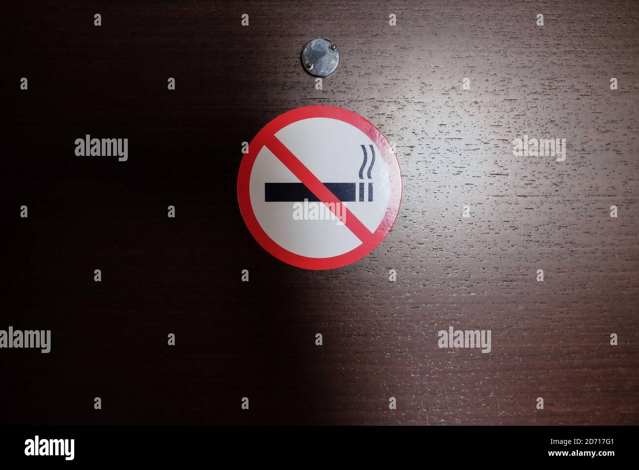 No smoking sign stuck on the wooden door of the hotel room. The crossed out cigarette. Concept signs, rules of conduct in public places, comfort, heal Stock Photo