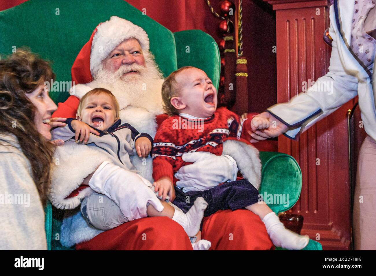 Virginia Norfolk MacArthur Center Mall,Santa Claus holds holding crying babies baby toddler toddlers,man male costume outfit mother trying tries comfo Stock Photo