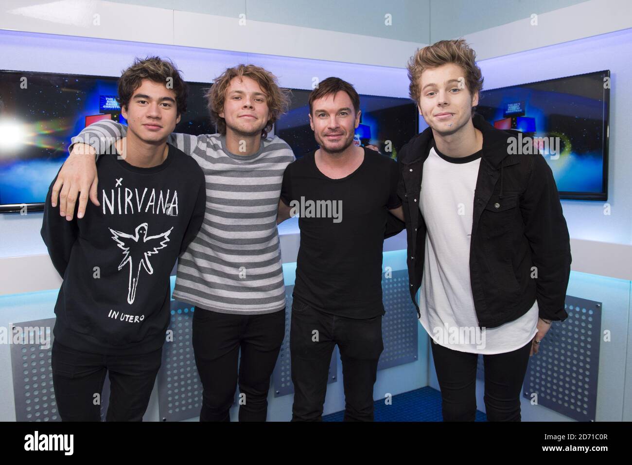 Calum Hood Ashton Irwin and Luke Hemmings of Seconds of Summer are interviewed by presenter Greg Burns at the Capital FM Jingle Bell Ball at the O2 arena in east London Stock