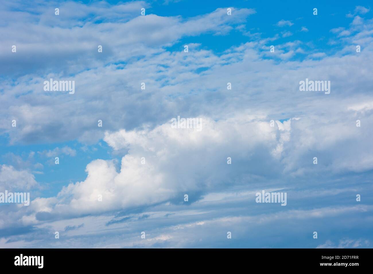 Large clouds and storm clouds close-up against a blue sky. White clouds are mixed with thunderclouds. Stock Photo
