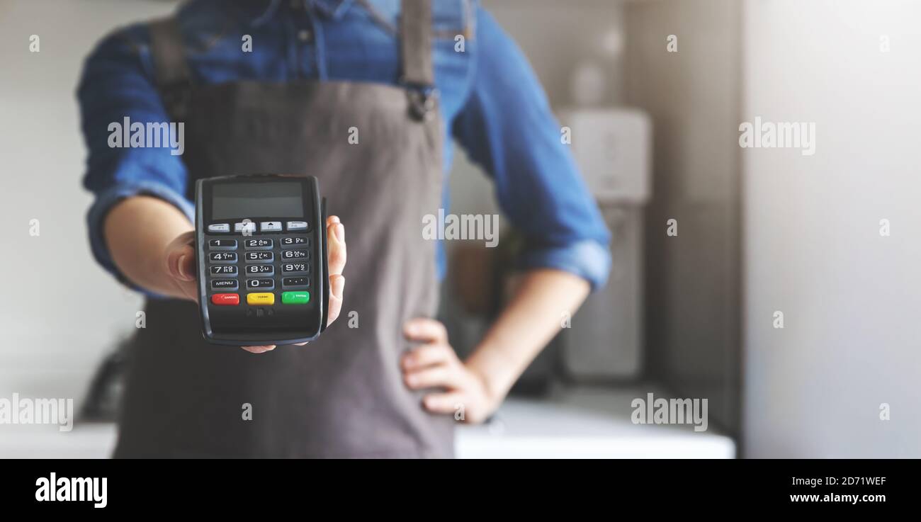 noncash payment - waitress with apron standing in cafe with pos terminal in hand. copy space Stock Photo