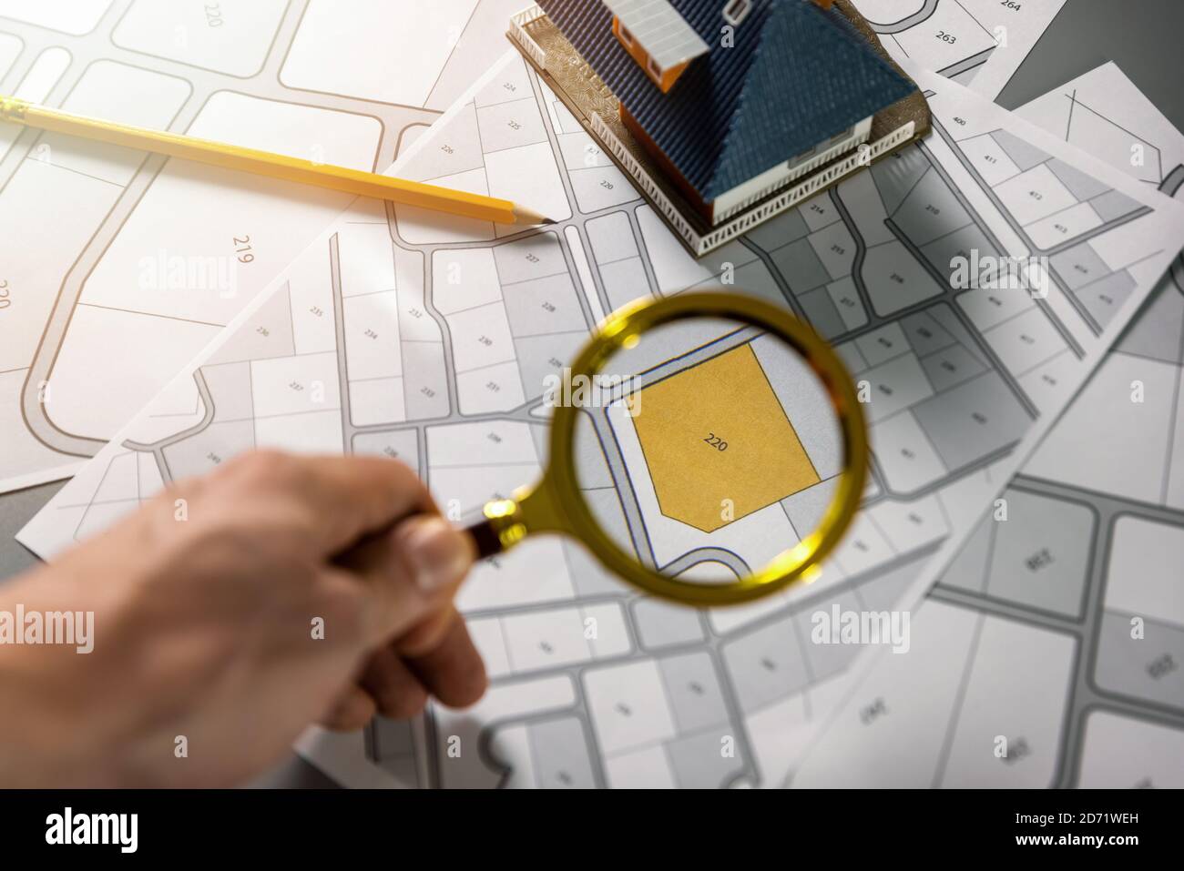 searching building plot for family house construction - hand with magnifier on cadastre map Stock Photo
