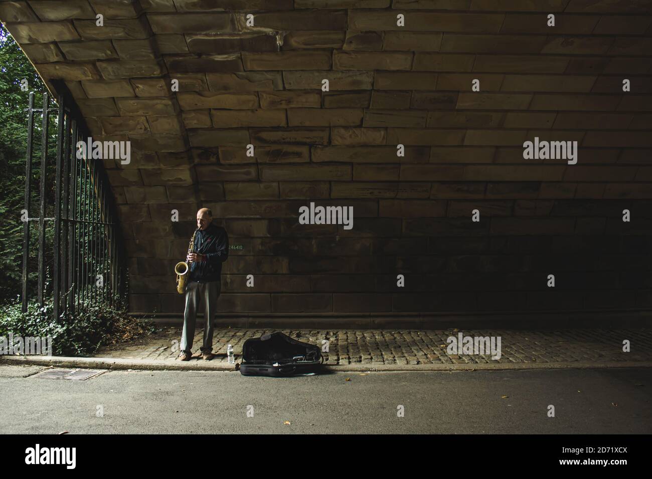 MANHATTAN, UNITED STATES - Sep 24, 2020: A an playing the saxophone under an arch in dim light in Central Park in New York Stock Photo