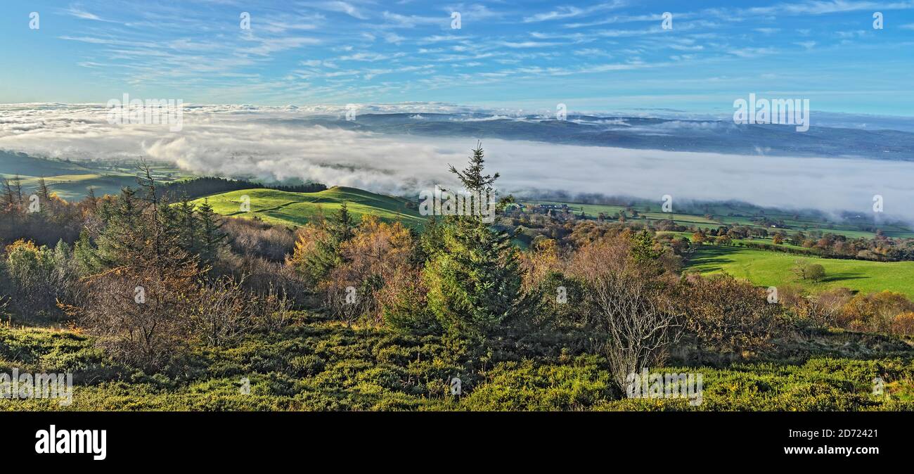 View from western slopes of Pennycloddiau Mountain in the Clwydian Range in morning light with low cloud streaming down the Vale of Clwyd  North Wales Stock Photo