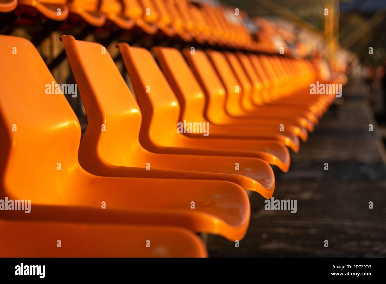Close up view of stadium seats on orange color, selective focus. Stock Photo