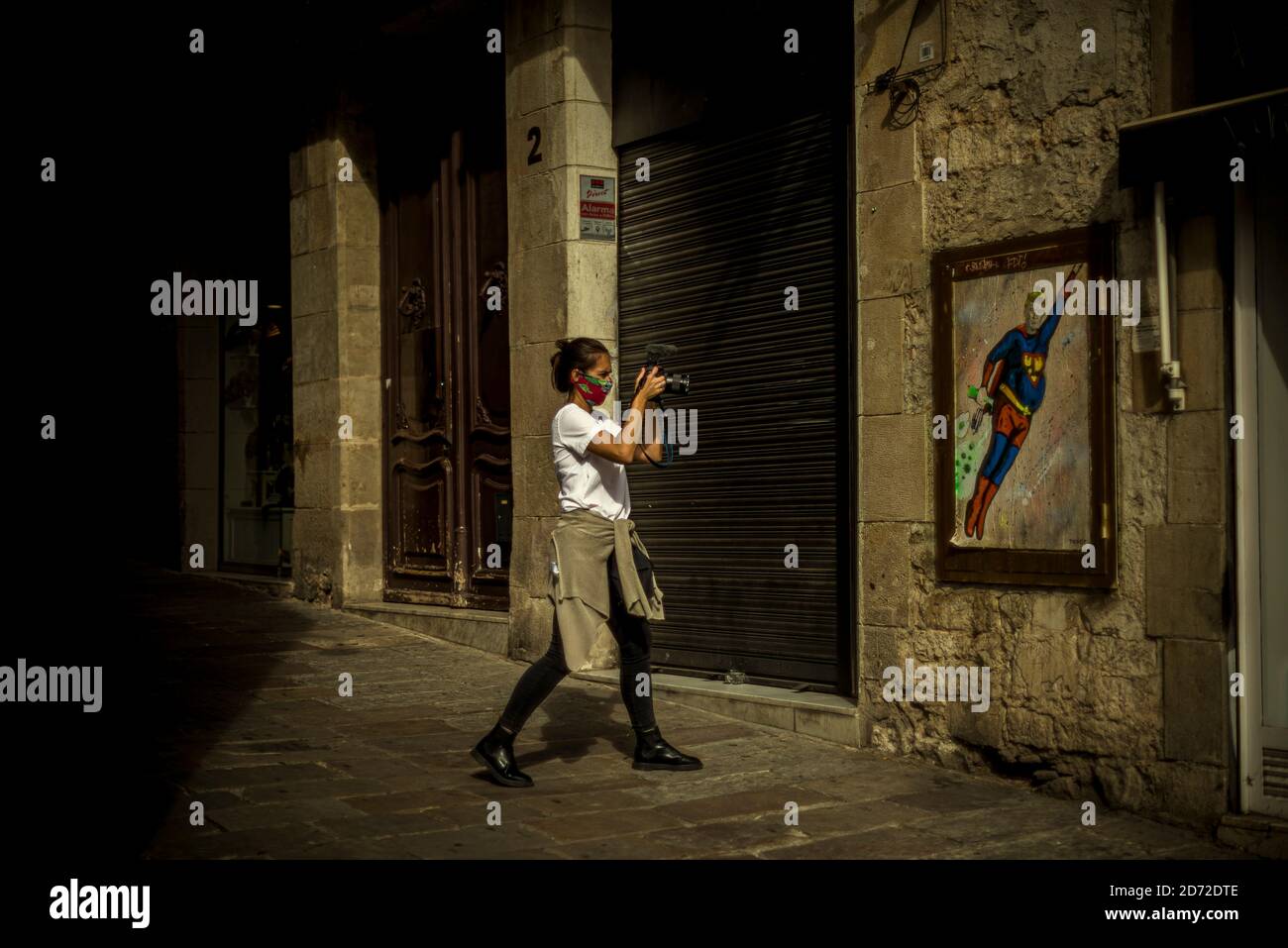 Barcelona, Spain. 20th Oct, 2020. A photojournalist takes a photo of a graffiti by Italian urban artist 'TVBoy', Salvatore Benintende, titled 'What doesn't kill you makes you stronger. Or not?' depicting US President Donald Trump wearing a Superman costume flying amid coronavirus clouds Credit: Matthias Oesterle/Alamy Live News Stock Photo