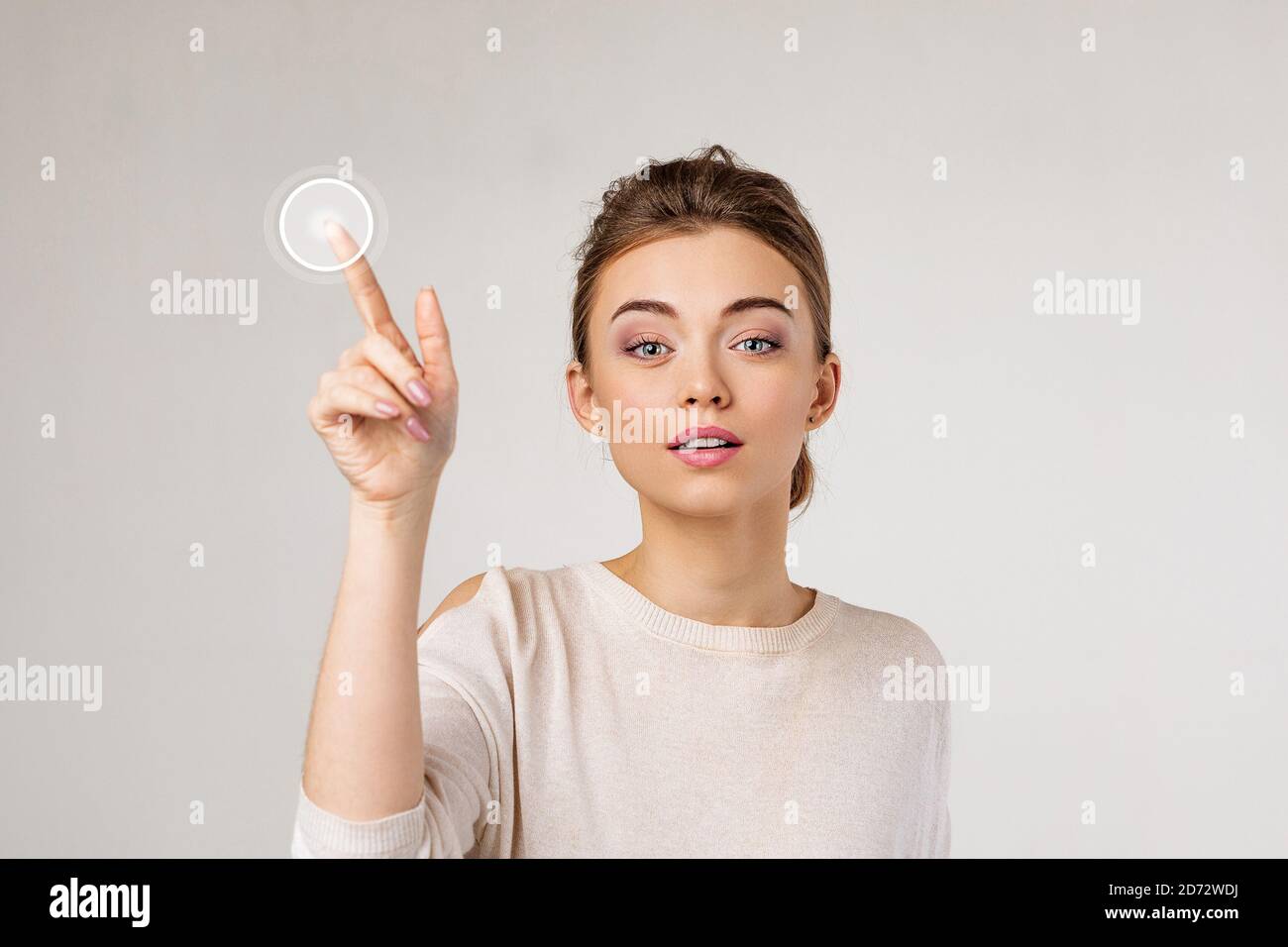 young beautiful woman pressing virtual button and looking at the camera on gray background. Stock Photo