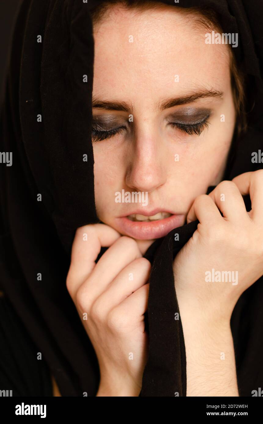 Portrait photograph of a Caucasian girl with closed eyes covered with a black sheet Stock Photo