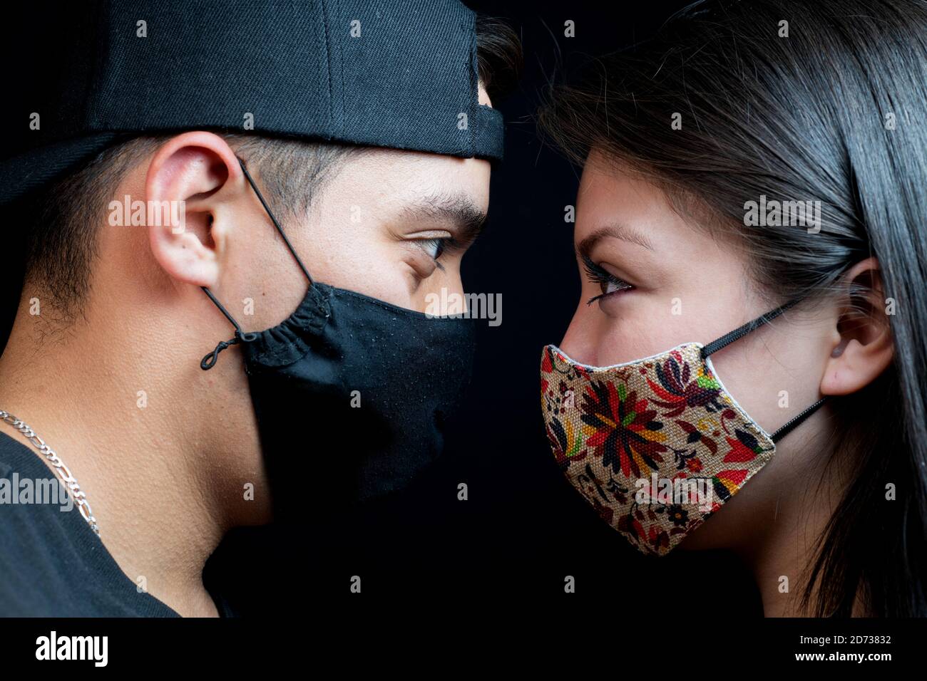 Man and woman looking at each other with mask and black background Stock Photo