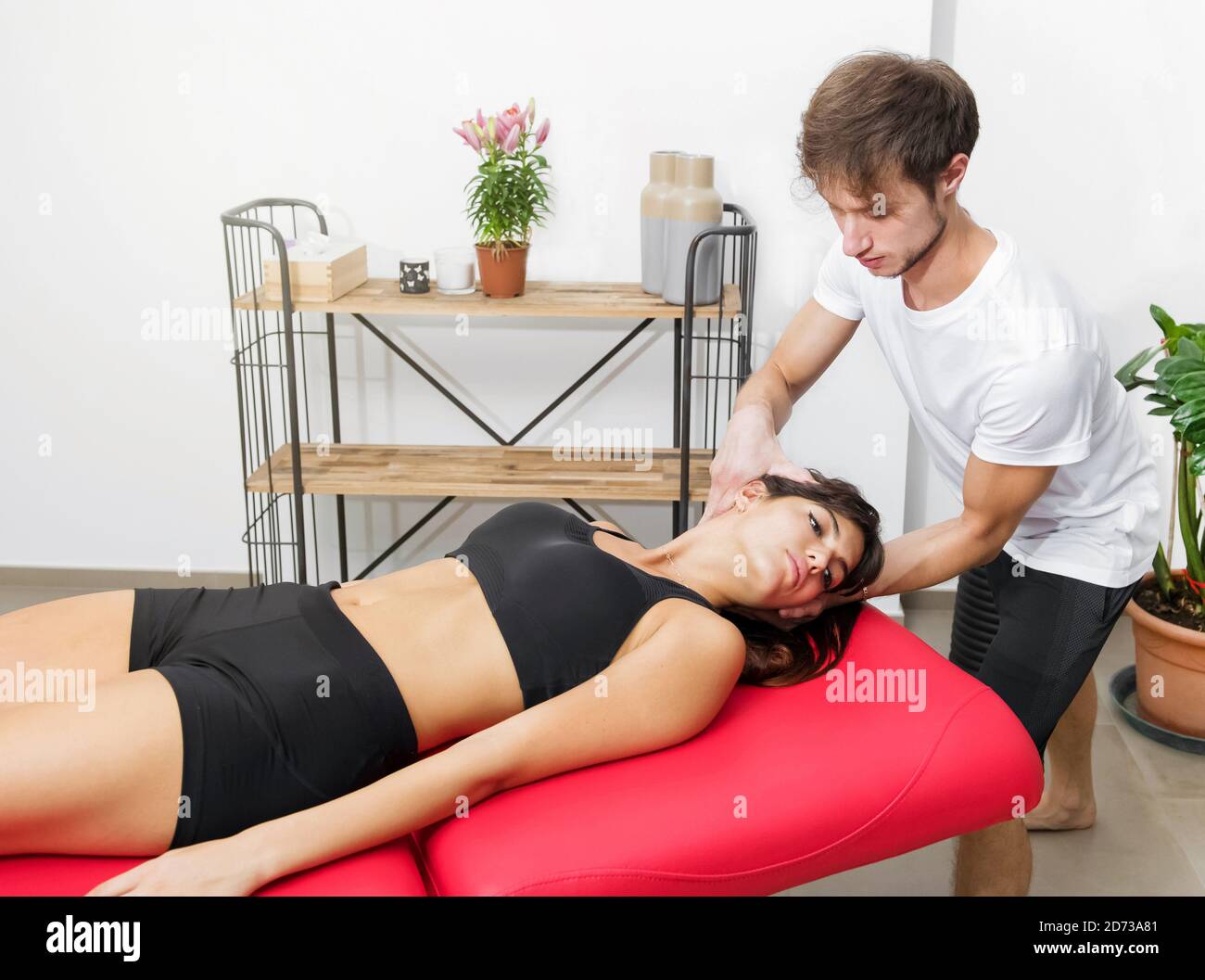 Osteopath performing cervical trust on a woman patient manipulating her spine during a consultation in his clinic Stock Photo
