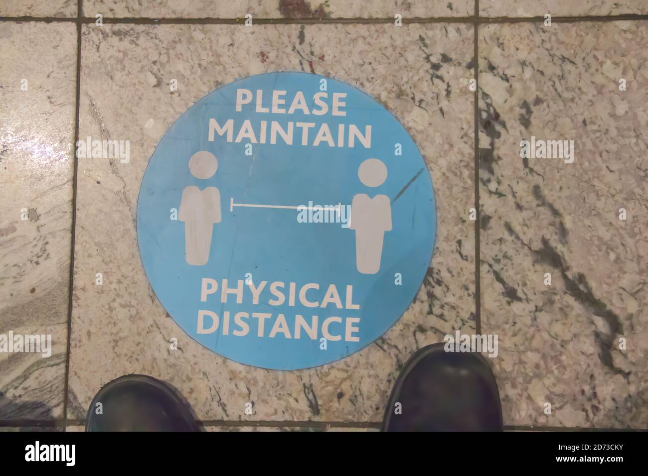 Sticker sign on the floor of public space, reminding people to keep and maintain physical the distance due to covid-19 outbreak Stock Photo