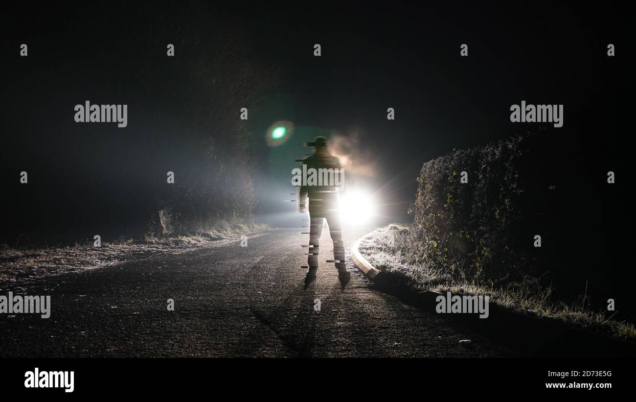 A digital glitch effect of a man standing on a road on a winters night. Back lighted by car headlights Stock Photo