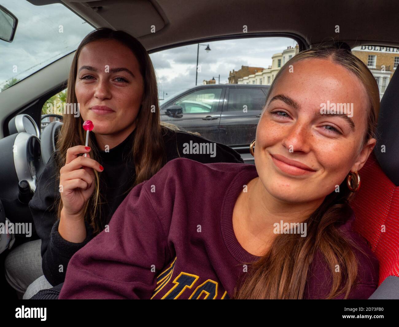 Two young women in the front of a car parked at Herne Bay beach. Stock Photo