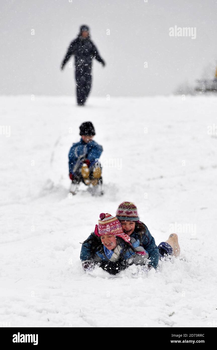 Children toboggan as Hampstead Heath lies covered in snow as a cold
