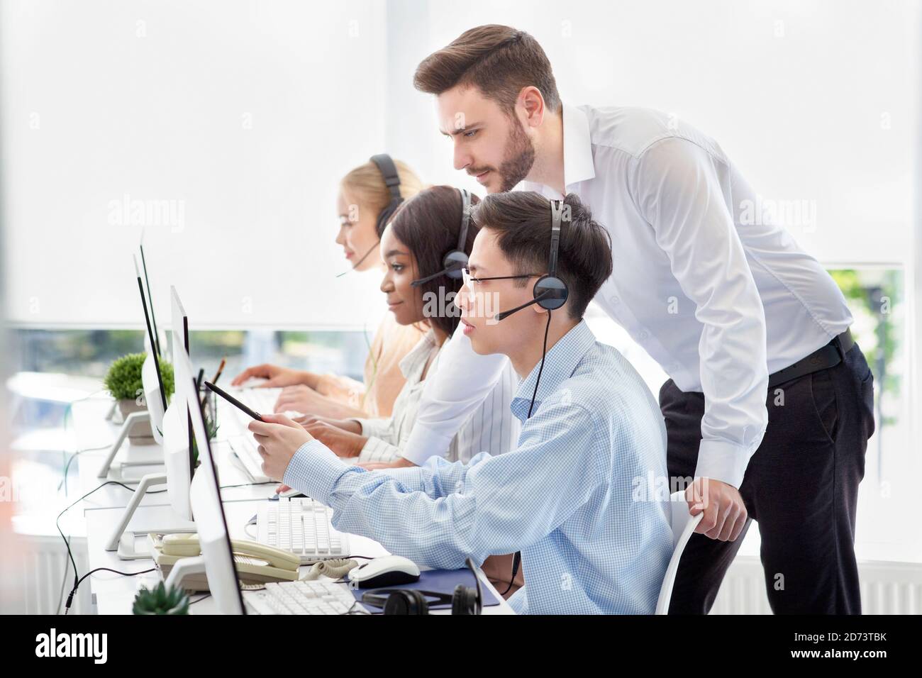Customer service administrator helping his supervisee to execute client's request at call centre Stock Photo