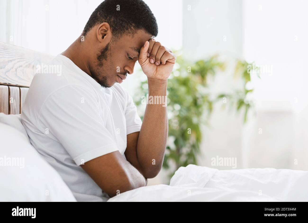 African American Man Suffering Depression Sitting In Bed At Home Stock Photo
