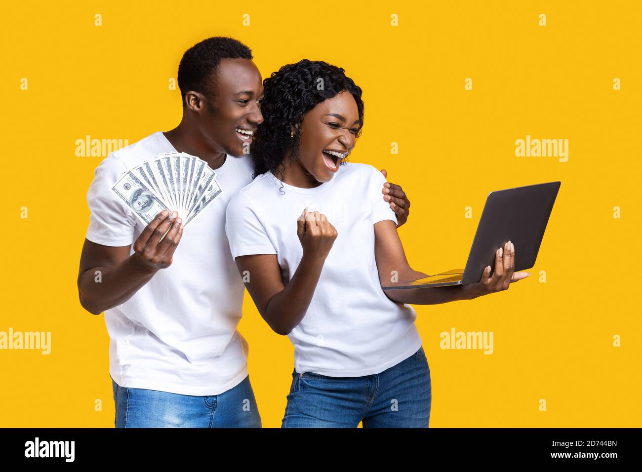 Emotional black couple celebrating win with laptop and cash Stock Photo ...