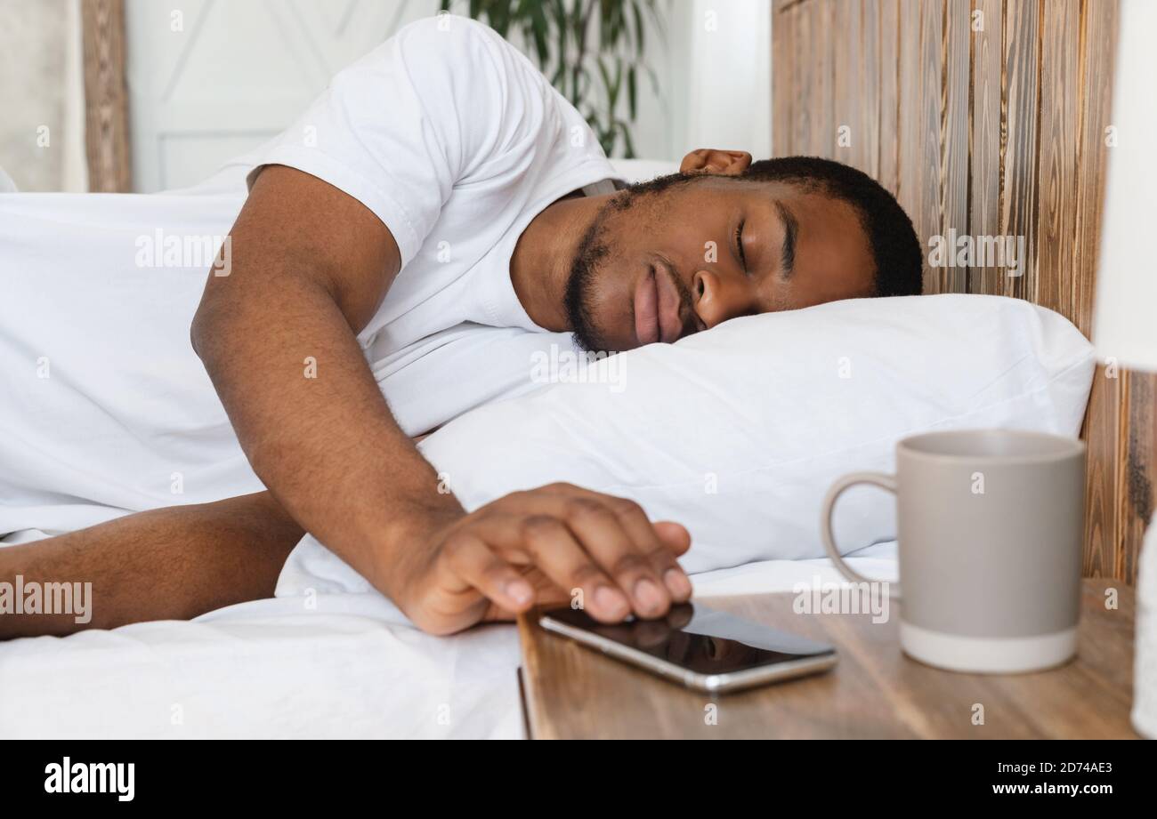 African Man Sleeping Through Alarm-Clock On Smartphone Lying In Bed Stock  Photo - Alamy