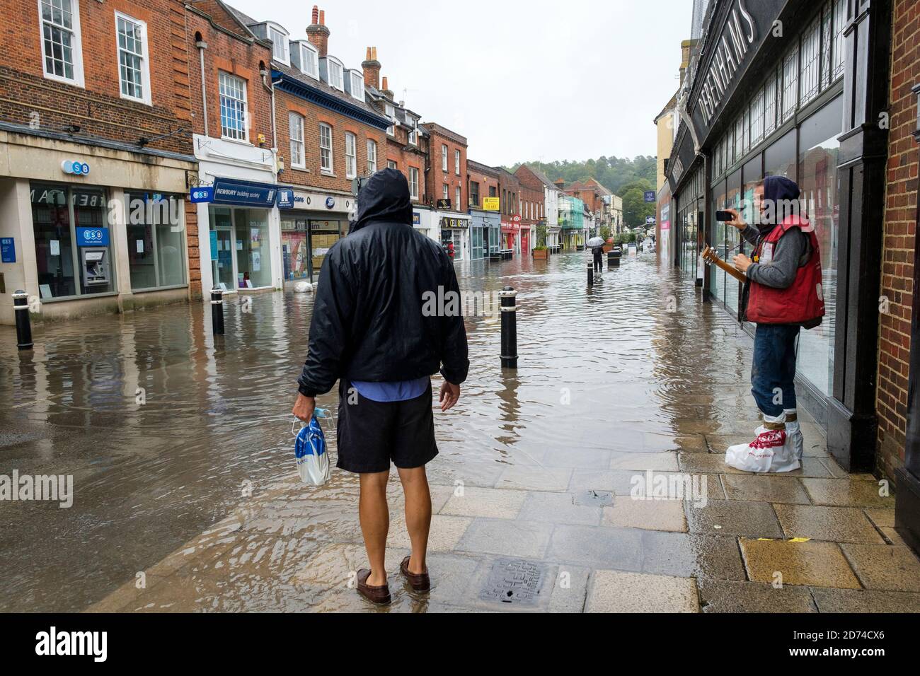 Winchester, England ,UK  27/08/2020 A busker takes a picture of the flooding on the High street in Winchester after heavy downpours due to storm Franc Stock Photo