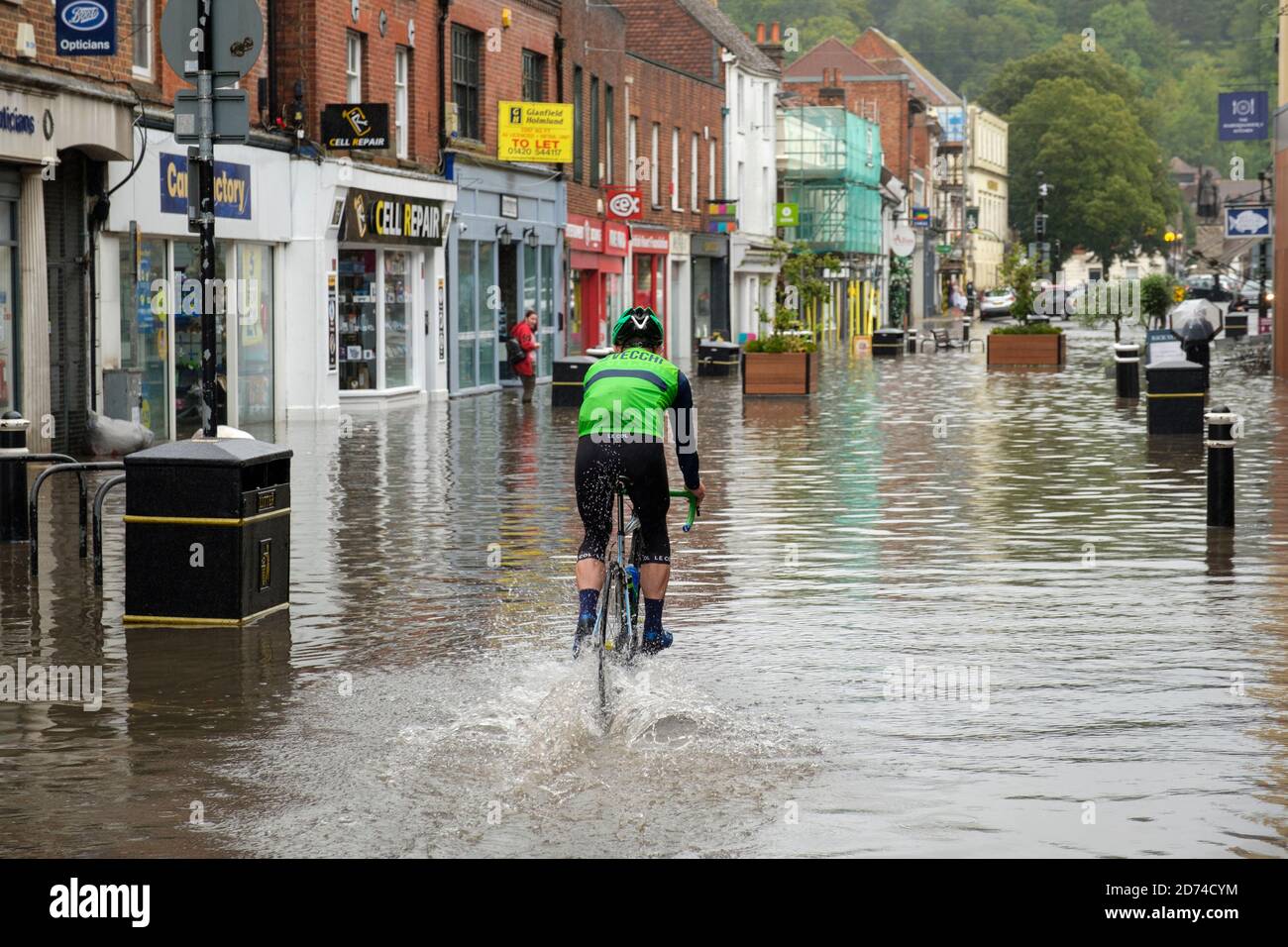 Winchester, England ,UK  27/08/2020 A cyclist riding through flood water on the High street in Winchester after heavy downpours due to storm Francis. Stock Photo
