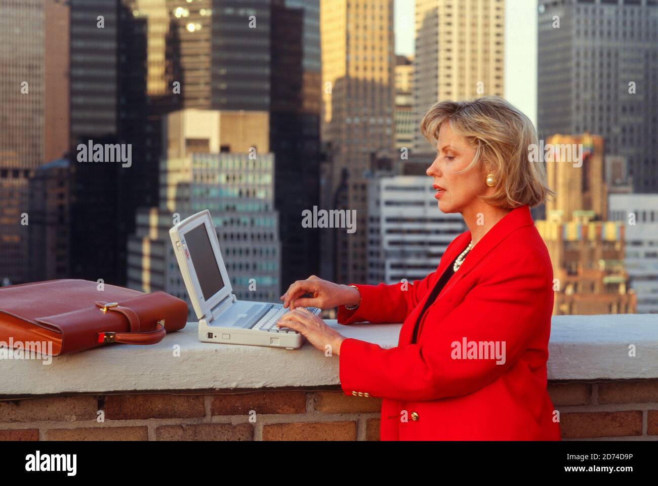 1990s Businesswoman Working on a Laptop computer on a Roof-deck in Midtown Manhattan, NYC, USA Stock Photo