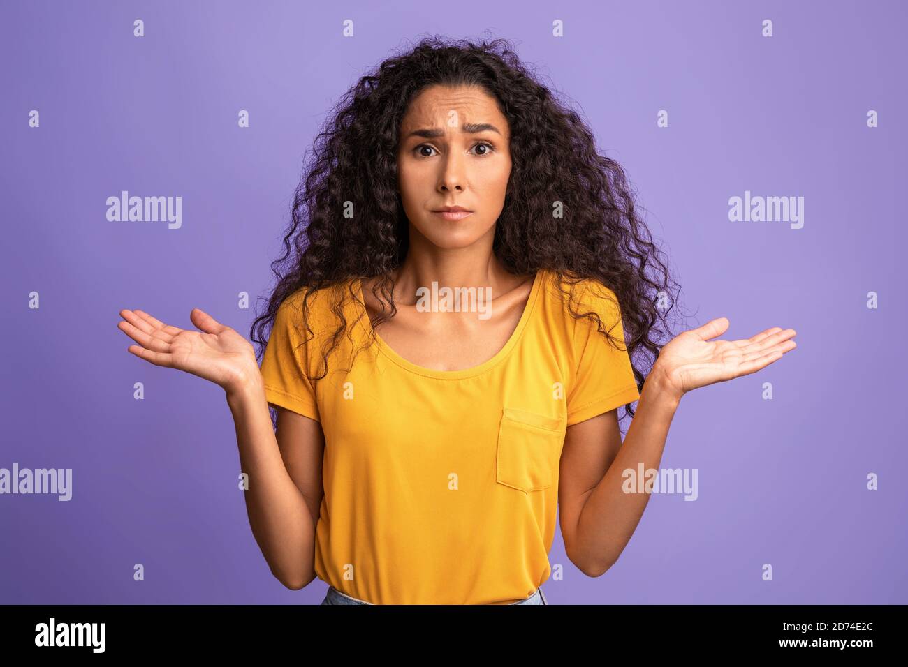 I Don't Know. Concerned young woman shrugging shoulders with spreaded hands Stock Photo
