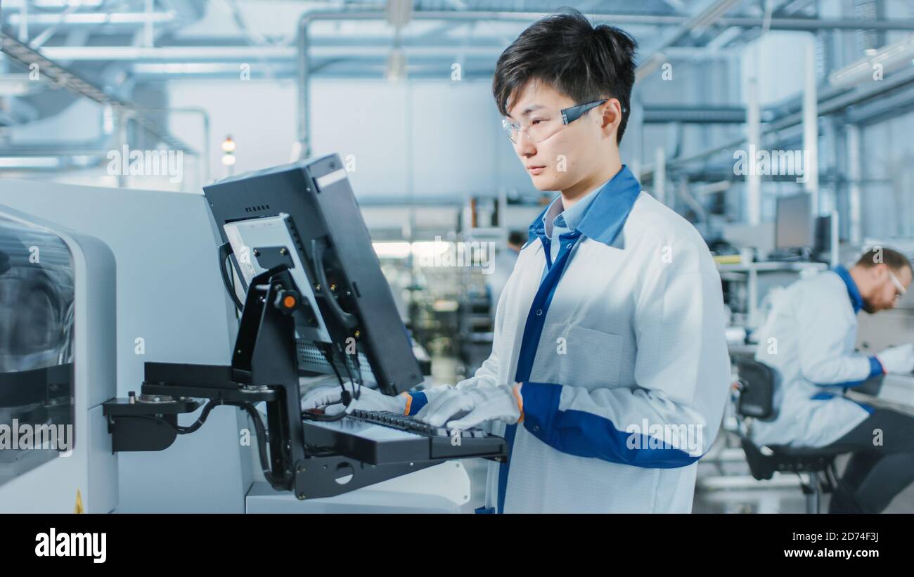 On High Tech Factory Asian Engineer Uses Computer for Programing Pick ...