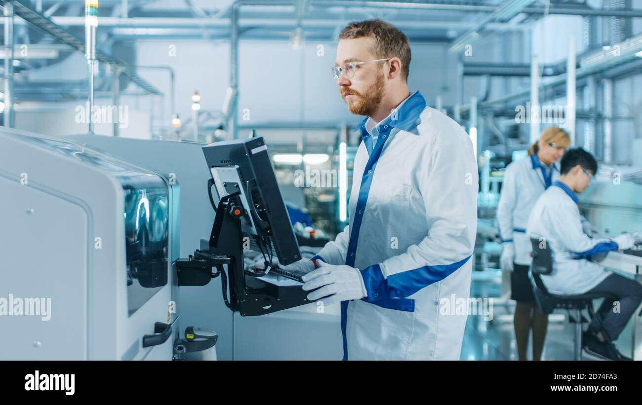 On High-Tech Factory Male Engineer Uses Computer for Programing Pick ...
