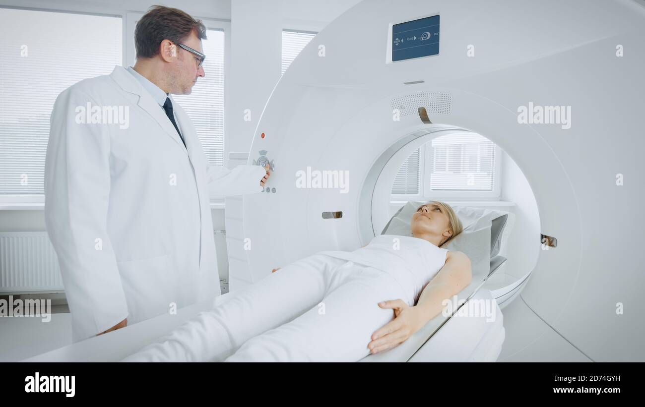In Medical Laboratory Radiologist Controls MRI or CT or PET Scan with Female Patient Undergoing Procedure. Professional Doctor Conducts Emergency Stock Photo