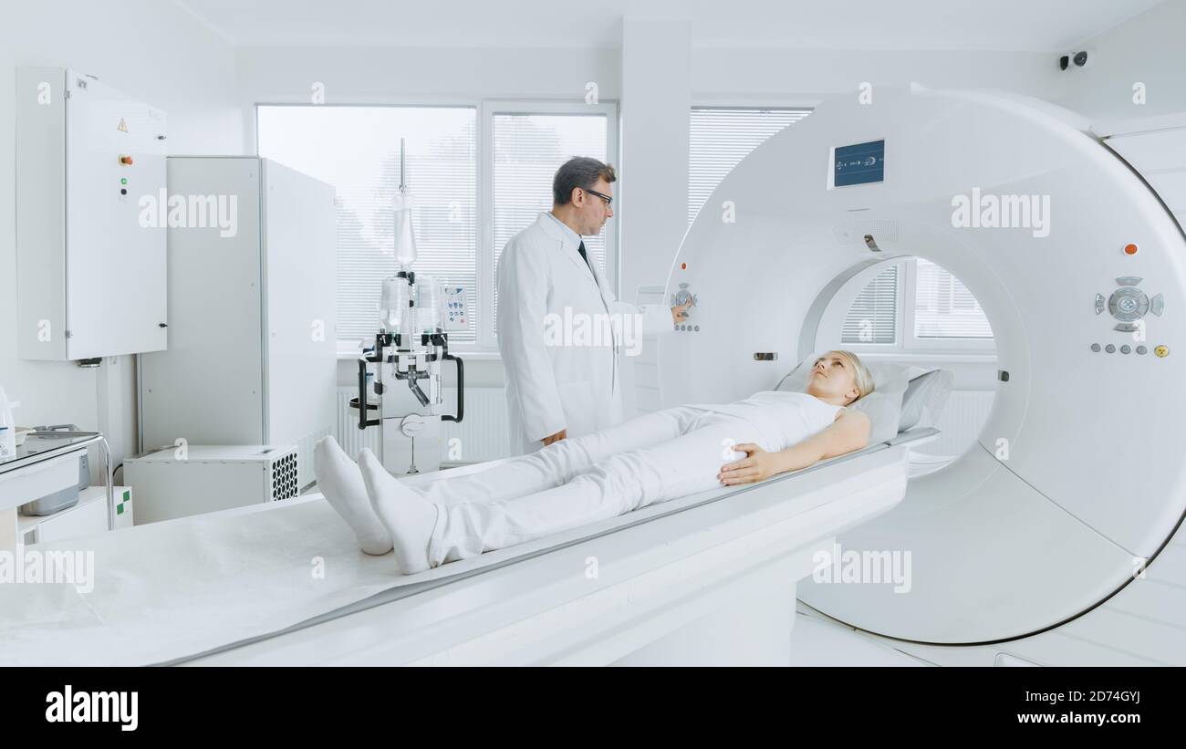 In Medical Laboratory Radiologist Controls MRI or CT or PET Scan with Female Patient Undergoing Procedure. Professional Doctor Conducts Emergency Stock Photo