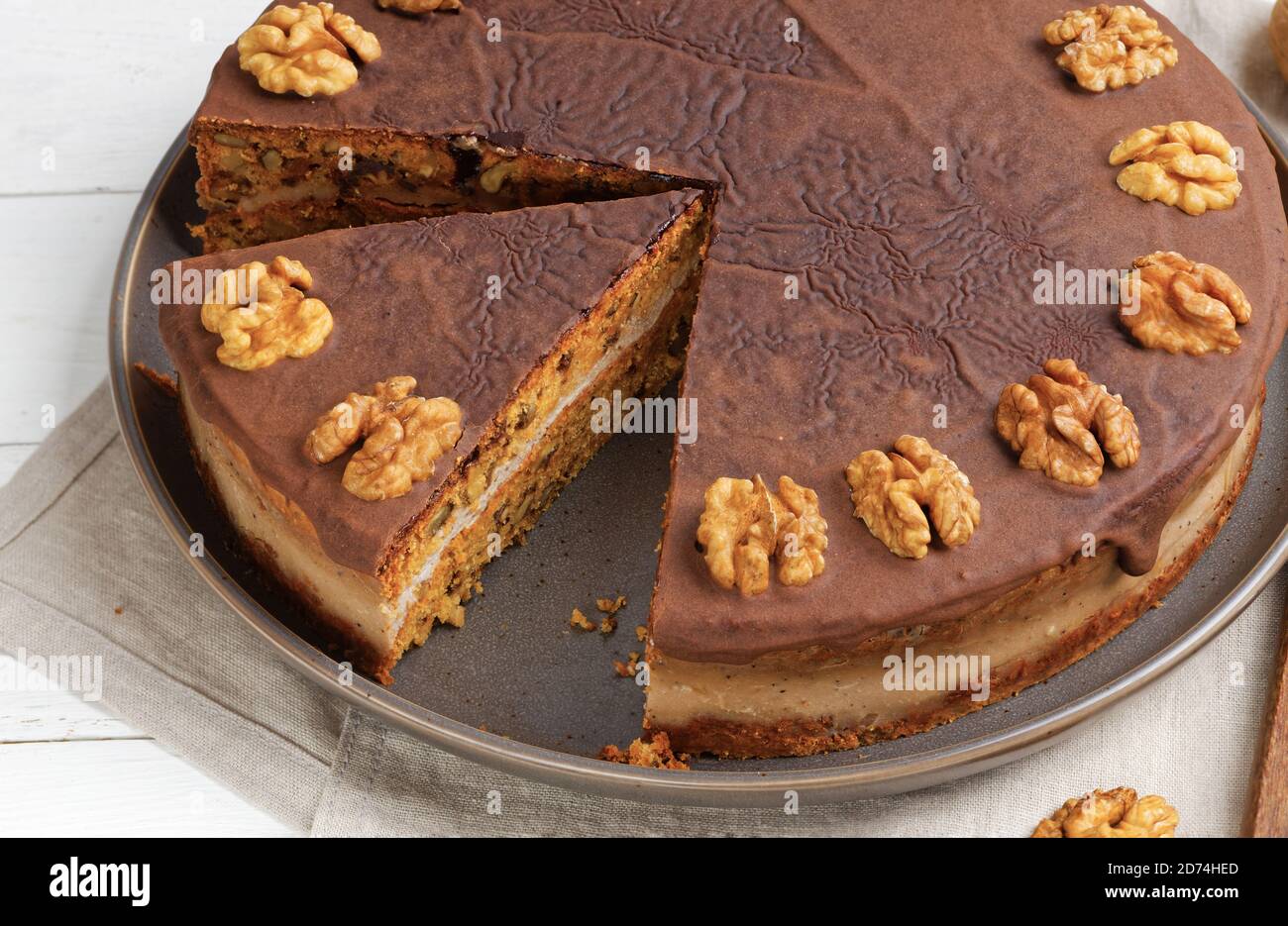Closeup homemade Walnut Cake with Chocolate Icing on white wooden table Stock Photo