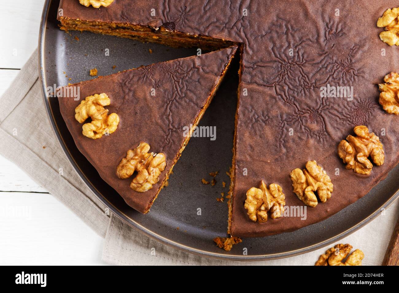 Closeup homemade Walnut Cake with Chocolate Icing on white wooden table. Top view. Stock Photo