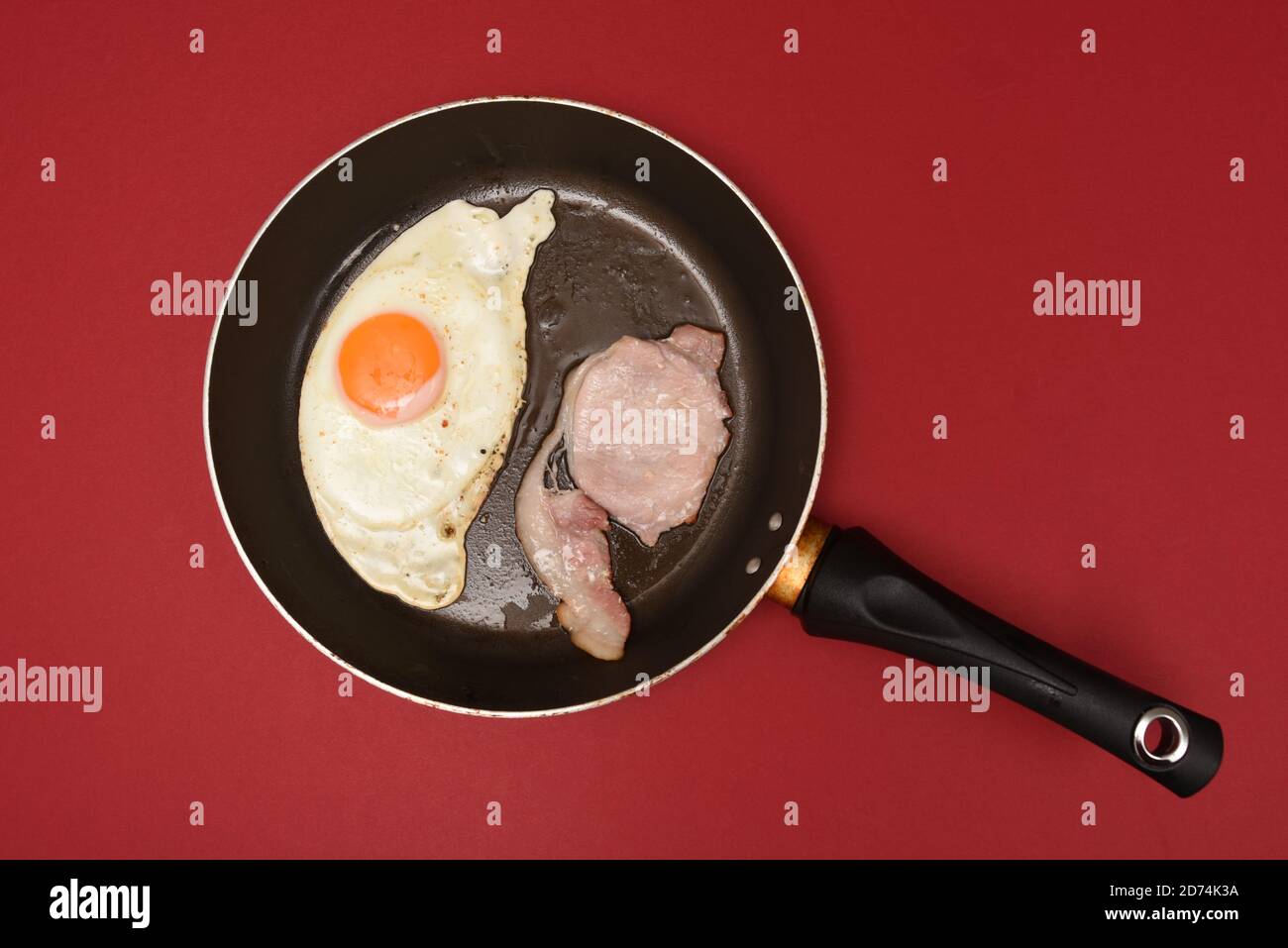 Fried egg and bacon in a pan Stock Photo