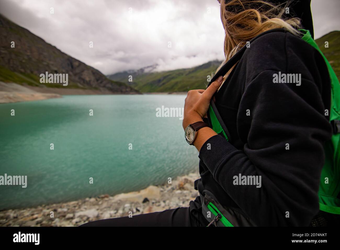 Woman taking break after sports training. She is standing with her hands on hips looking to the clear lake at cloudy day. Female athlete in wearing a Stock Photo