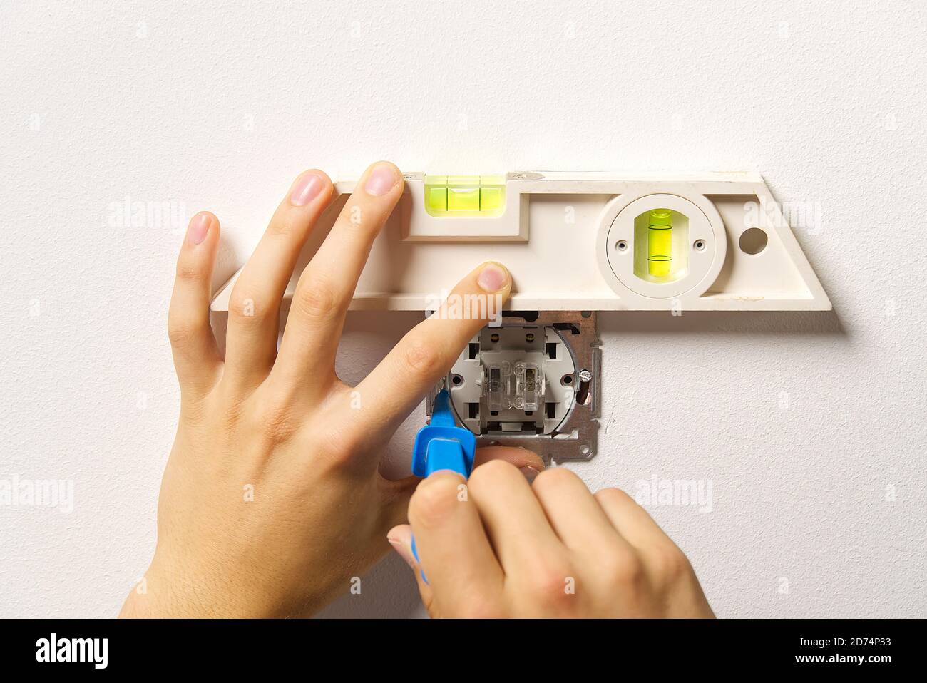 electrician installing light switch on painted wall with screwdriver