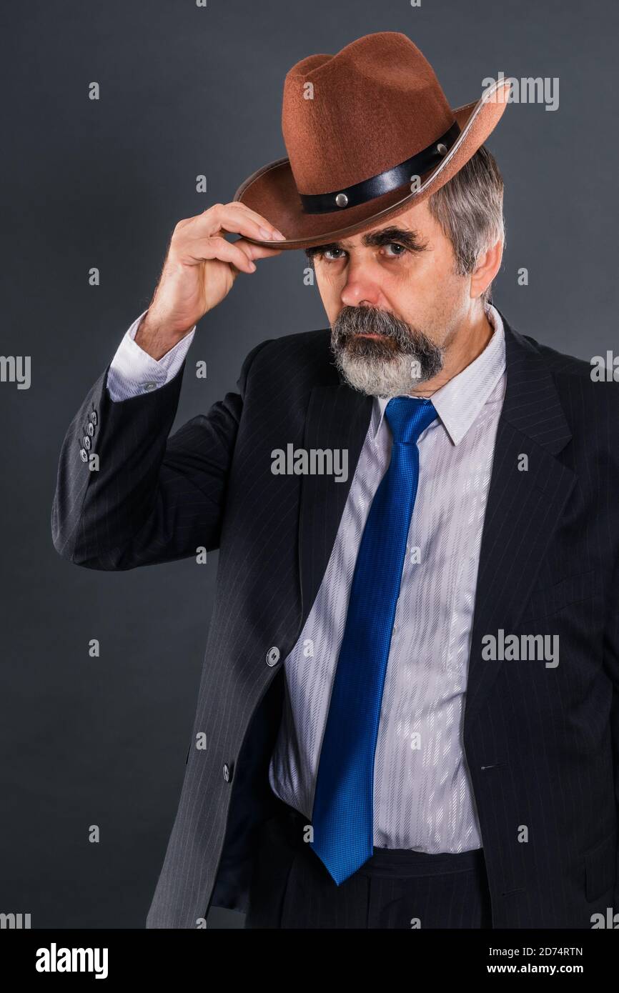Elderly dandy man in a suit with a tie takes off his hat for a greeting Stock Photo