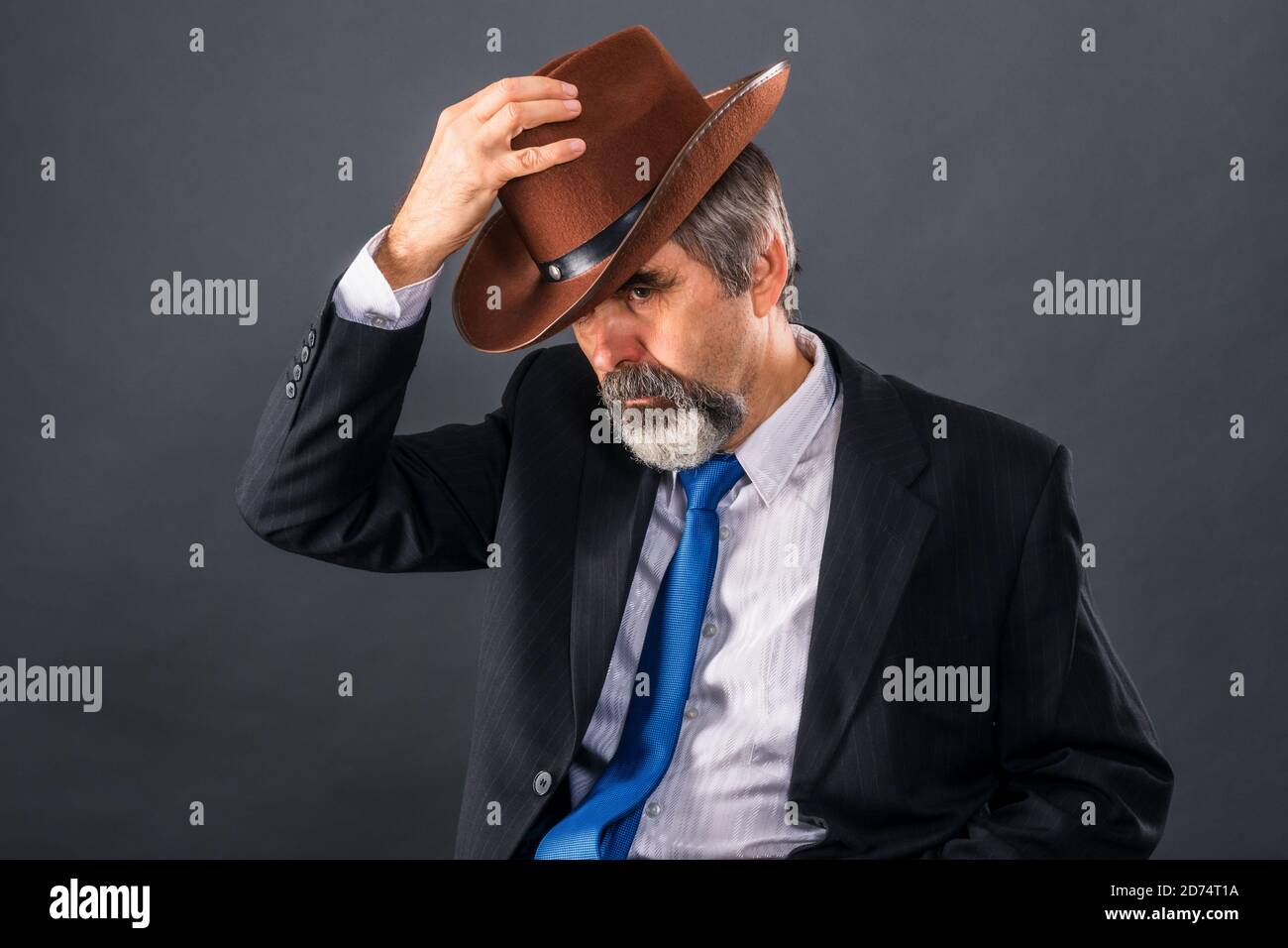 Elderly dandy man in a suit with a tie takes off his hat for a greeting Stock Photo