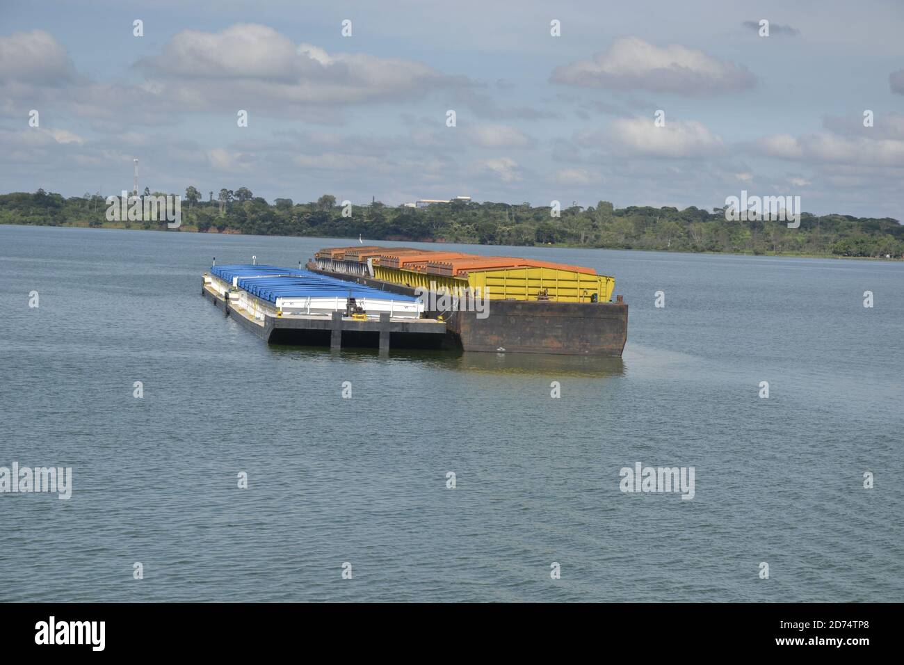Cargo boat, transporting products in a navigable freshwater river, waterway, with margin and vegetation in the background in panoramic photo and sky w Stock Photo
